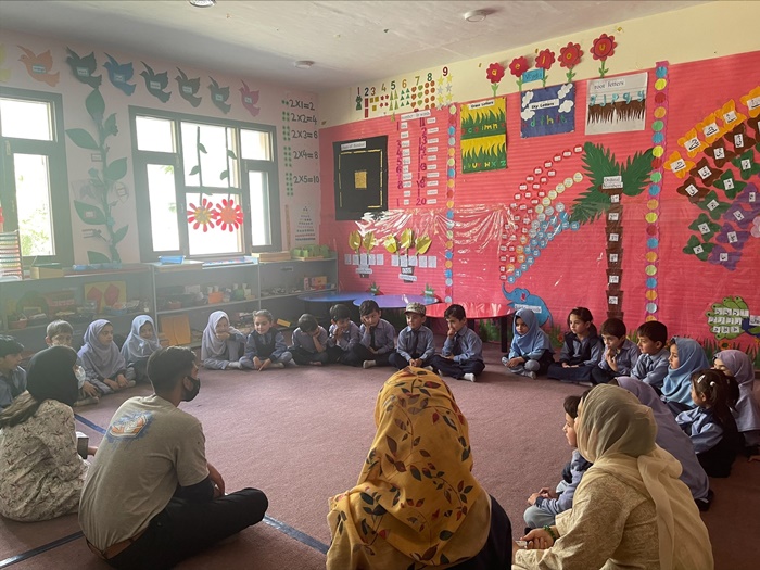 Team with students in an indoor classroom sitting in a circle